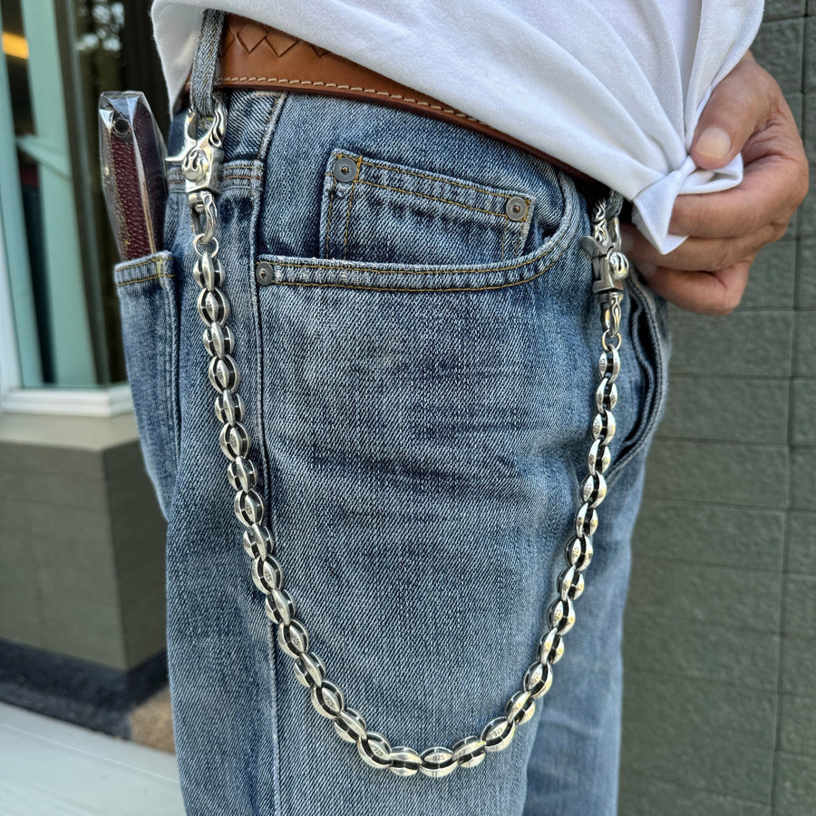 Un hombre llevando la cadena de billetera de flor de llama de plata esterlina pesada con jeans azules.