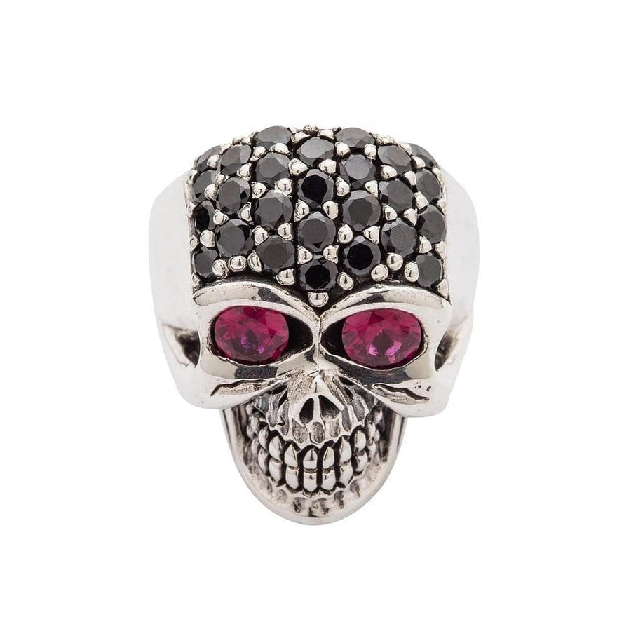 An anillo de plata esterlina con forma de cráneo femenino, cuyo cráneo está completamente pavimentado con cristales negros y dos ojos grandes y profundos de piedra roja.
