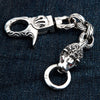 A 77-gram solid silver lion head biker keychain with red eyes, on dark denim.