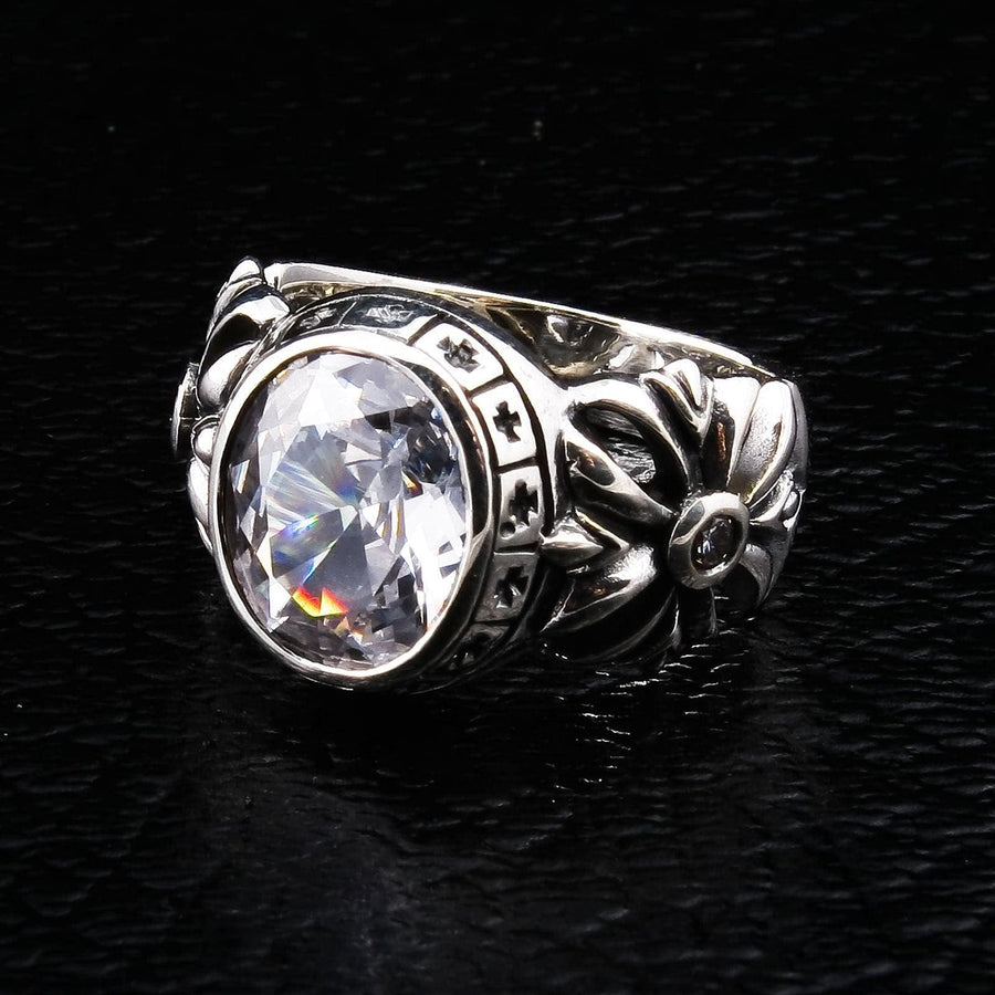 Un anello solido in argento sterling per uomo con un grande topazio bianco e una fascia intagliata con una croce floreale gotica.