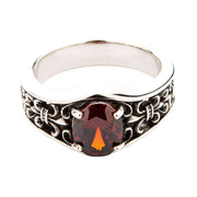 A men's solid sterling silver ring featuring a large oval garnet and a band carved with the Fleur de Lis symbol.