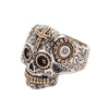 Angled view of sterling silver Calavera ring featuring brass floral eye details
