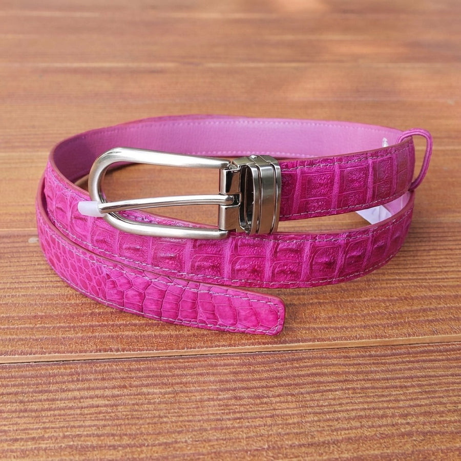 Cinturón de cuero de cocodrilo rosa para mujer con hebilla de plata enrollado sobre una superficie de madera