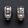 Pereche de cercei huggie tip inel cu cranii din argint sterling .925, fiecare bandă de 6 mm sculptată cu un rând de cranii cu ochi din zirconiu cubic roșu.
