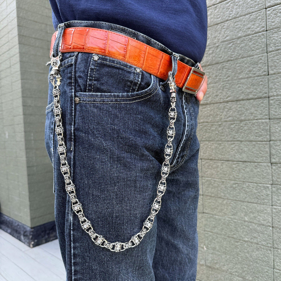 Uomo con una catena di portafoglio in argento sterling pesante indossata su jeans blu con cintura arancione