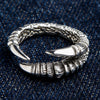 Anillo de garra de águila en plata de ley maciza con un imponente diseño envolvente, mostrado sobre un fondo de mezclilla oscura.