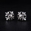 A pair of sterling silver skull and crossbones stud earrings with gothic filigree details, on a black background.