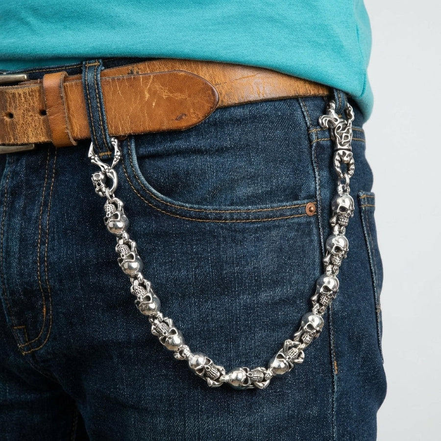 Cadena para cartera con calavera en plata de ley sujeta a una trabilla de vaqueros oscuros, mostrando su longitud total de 22 pulgadas.