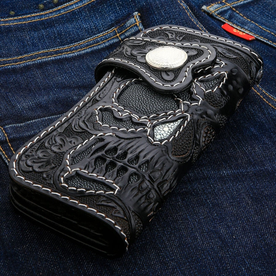 Le côté du long portefeuille de motard avec l'incrustation de crâne en galuchat gris, présenté sur du denim.
