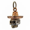 Un colgante de calavera de azúcar mexicana de tres metales, elaborado a mano con plata esterlina, latón y cobre, y un sombrero.