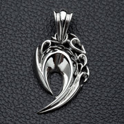 A front view of the sterling silver tribal fang pendant with flame engravings, resting on a black leather surface.