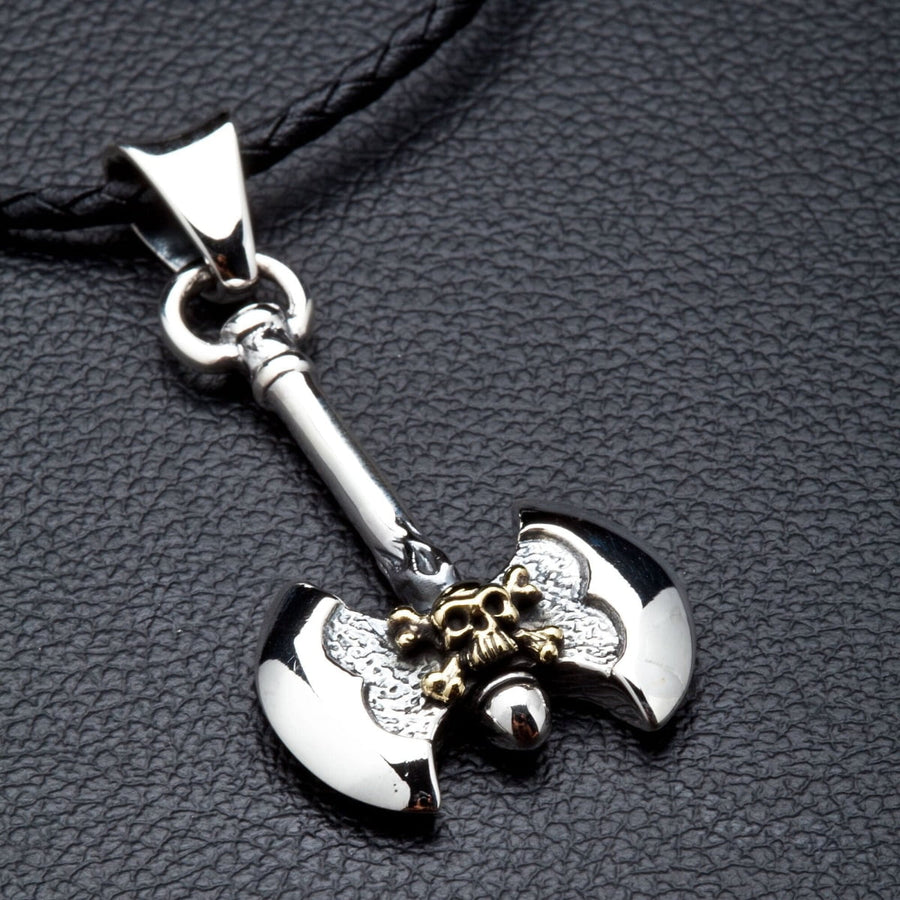 Een sterling zilveren Viking-bijl hanger met een messing doodskopdetail, getoond aan het bijgeleverde zwarte leren koord.