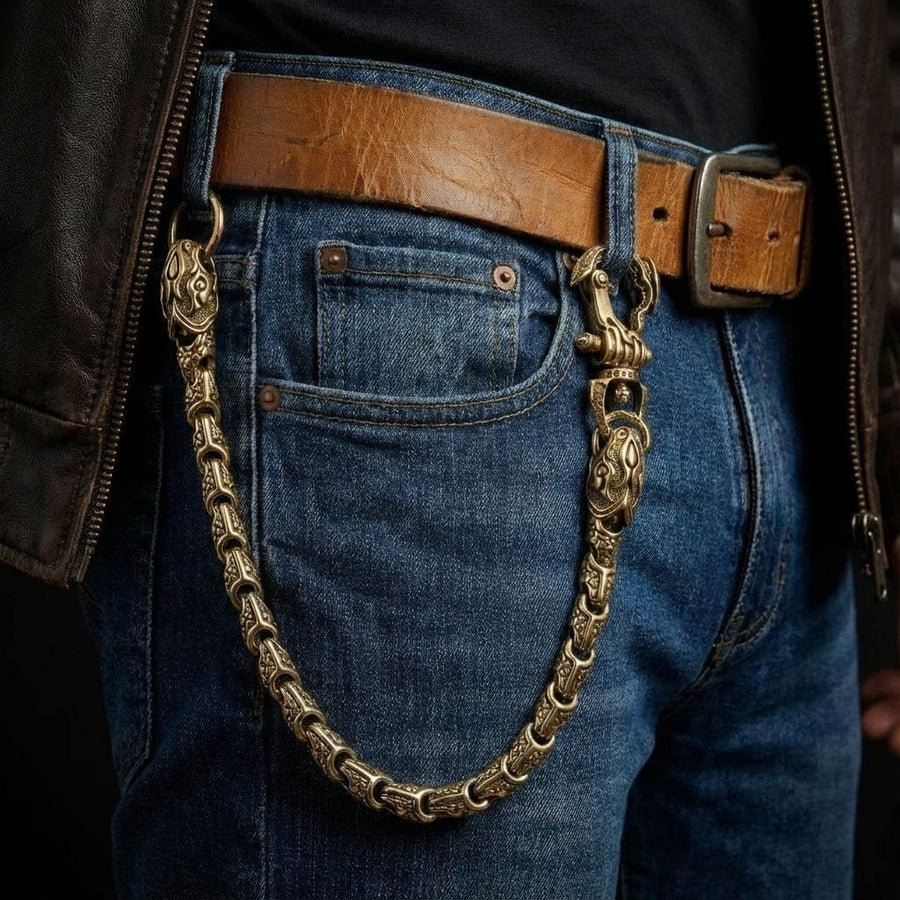 モデルがジーンズのベルトループに取り付けられた無垢の真鍮製バイパー・スネーク・ウォレットチェーンを身に着けており、複雑な蛇の鱗のディテールと重厚なバイカージュエリースタイルを披露しています。
