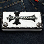The handmade white leather biker wallet with a black stingray cross inlay and silver snaps, resting on blue jeans.