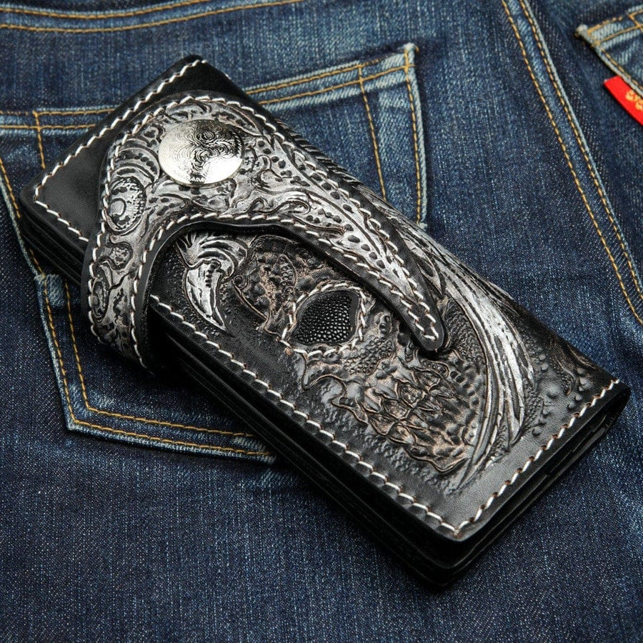 Handskuren biker-plånbok med bevingad dödskalle – framifrån med detaljerad lädergravyr och inlägg av svart rocka på denim