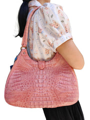 A woman wearing the genuine pink crocodile leather shoulder bag, showing its size and hobo style.
