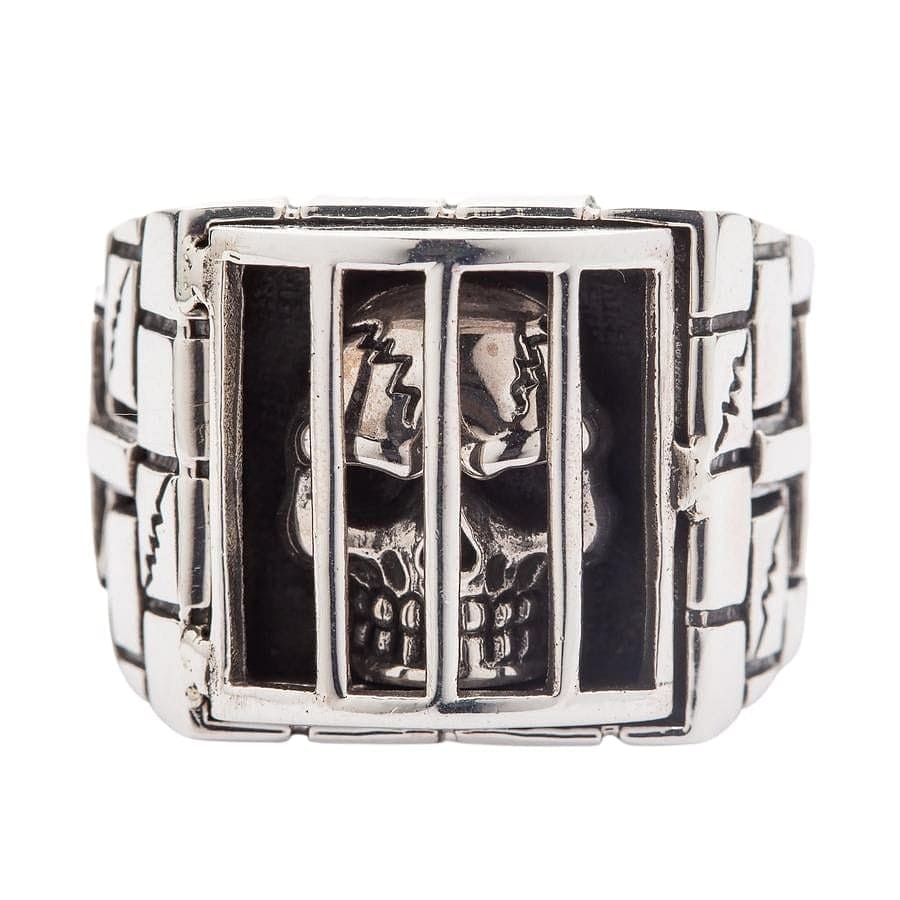 A premium, handcrafted gothic-style 'skull in jail' ring with a hand-carved stone wall band.