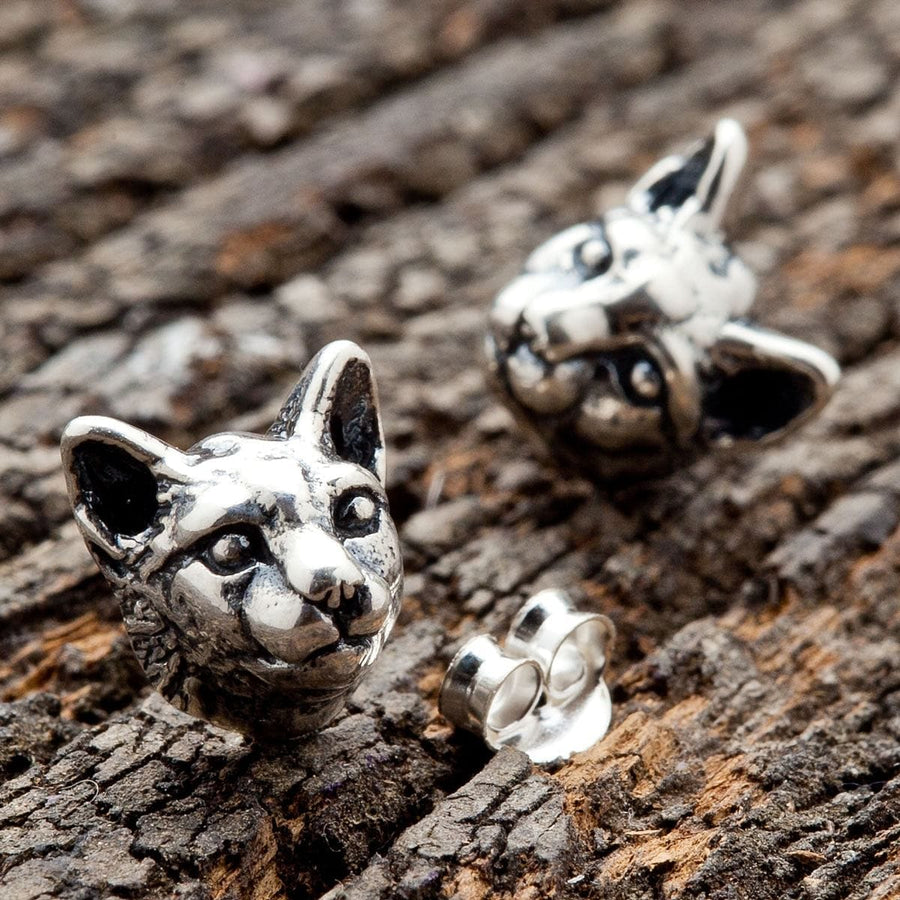 Pair of oxidized sterling silver cat head stud earrings with pointed ears and a loose butterfly backing beside them