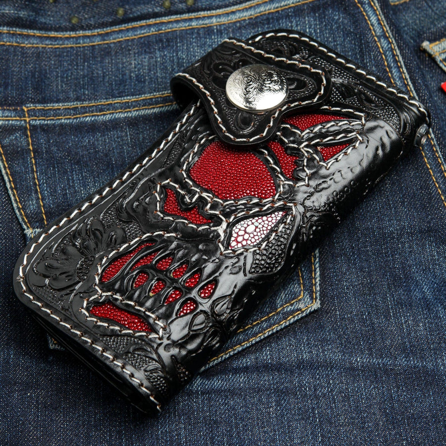Die handgeschnitzte Lederbrieftasche Phantom Skull mit roter Stachelrochen-Intarsie, abgebildet auf einer Jeans.