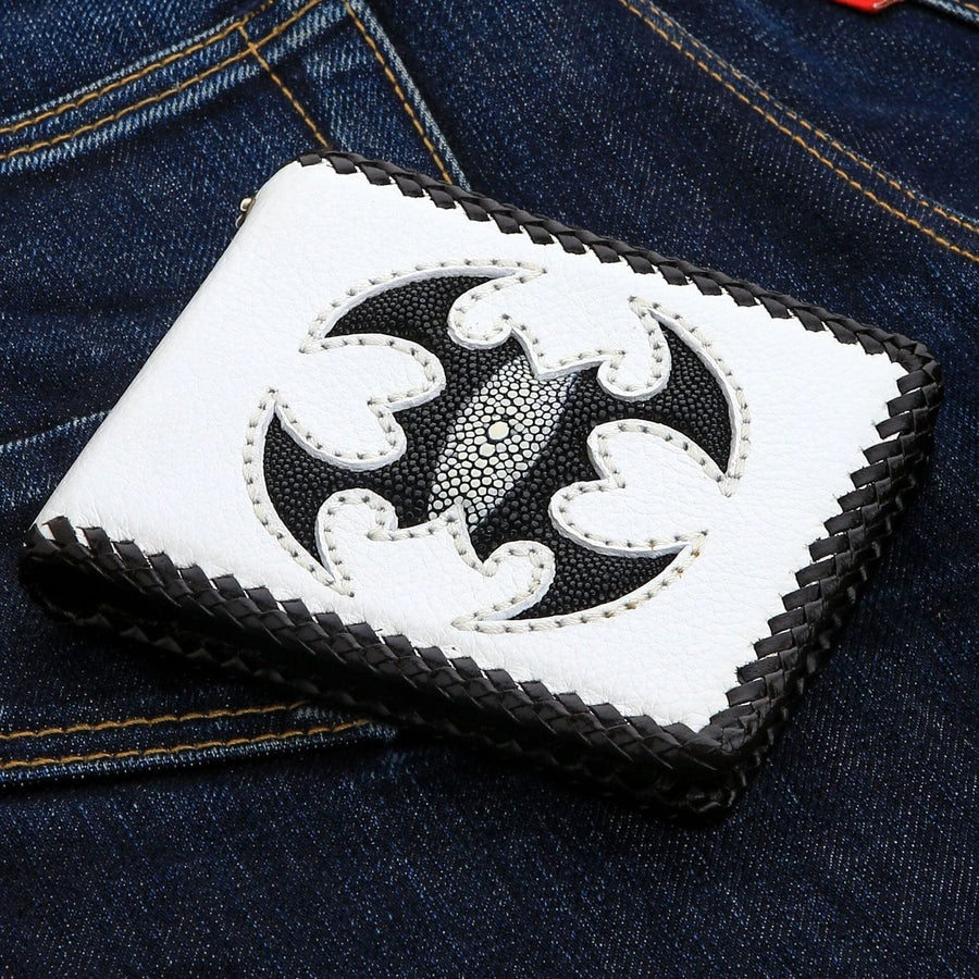 De handgemaakte witte leren biker portemonnee met een zwarte stekelrog schorpioen inleg, rustend op blauwe jeans.